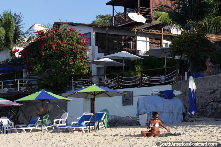 Woman enjoys the sun and houses behind at Pipa Beach. (720x480px). Brazil, South America.