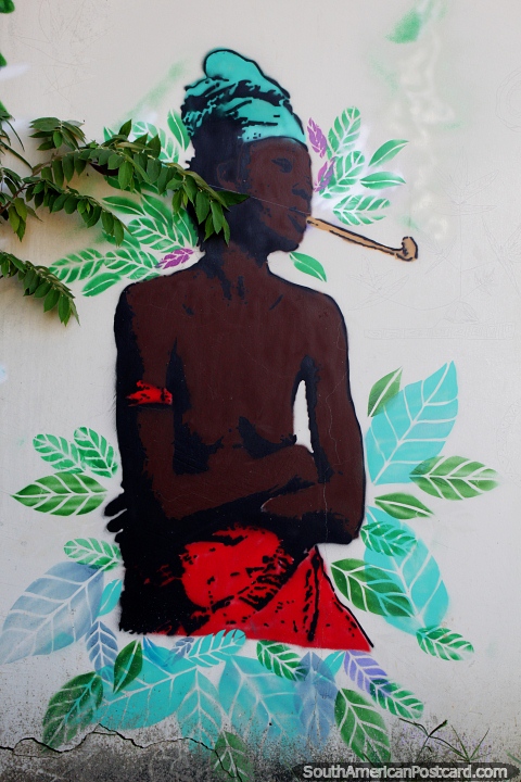 A native man wearing red and green smokes a pipe, street art in Rio Branco. (480x720px). Brazil, South America.