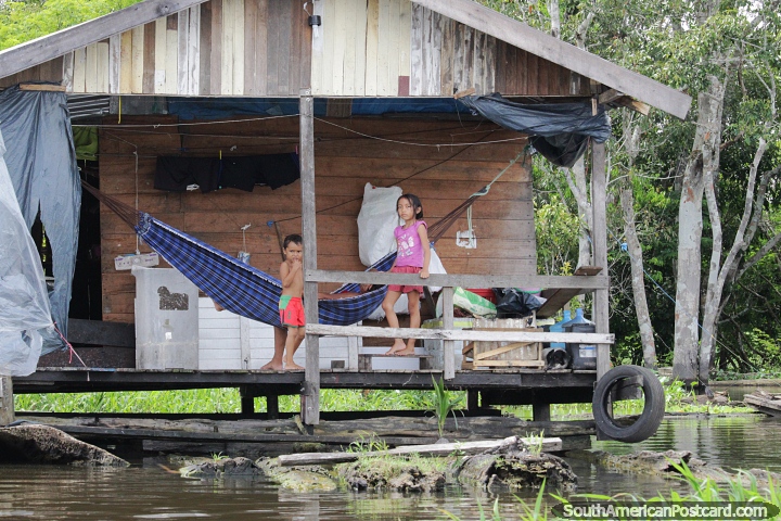Kids outside a house built over the water across the river from Manaus city. (720x480px). Brazil, South America.