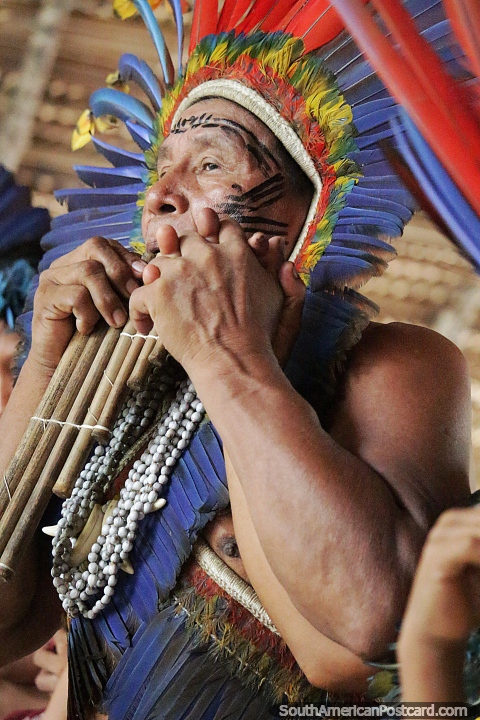 Shaman wears colored feathers and blows wooden pipes, the Amazon, Manaus. (480x720px). Brazil, South America.