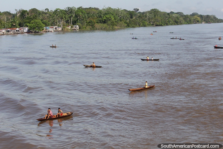 Crianas de uma aldeia amaznica esperam em canoas por presentes jogados por passageiros de uma balsa que passa. (720x480px). Brasil, Amrica do Sul.