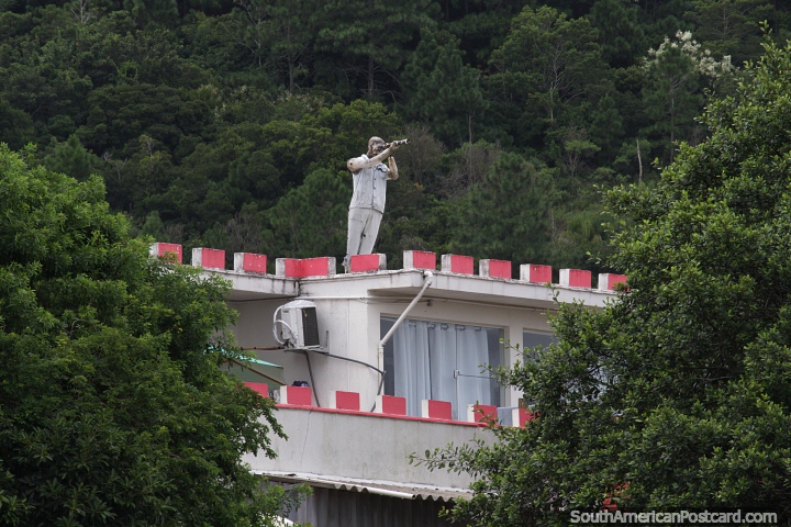 Hombre usando un telescopio desde lo alto de una casa en Barra da Lagoa en Florianpolis. (720x480px). Brasil, Sudamerica.