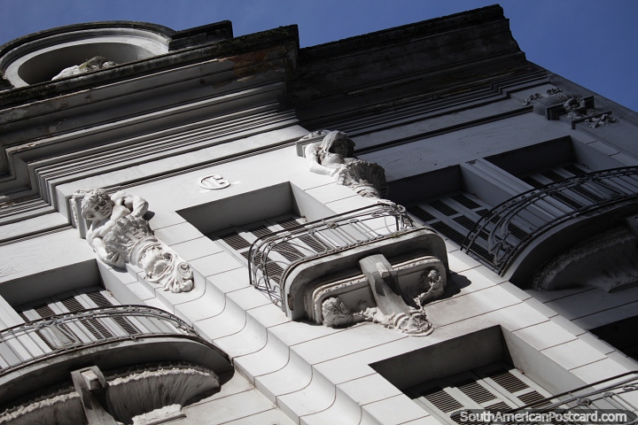 Figuras miran hacia abajo desde lo alto de la fachada de un edificio en Porto Alegre. (720x480px). Brasil, Sudamerica.