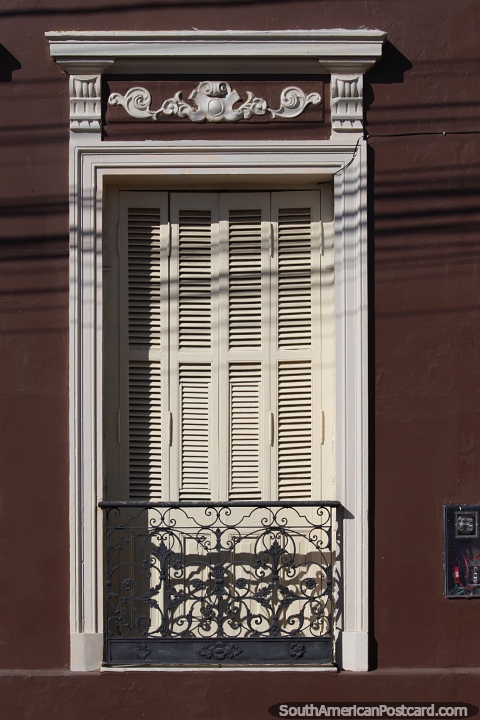 Window with wooden shutters, iron balcony and ceramic decoration above it in Alegrete. (480x720px). Brazil, South America.