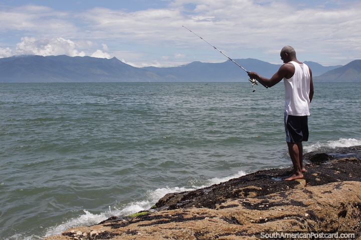 Homem pescando nas rochas do litoral de Caraguatatuba. (720x480px). Brasil, Amrica do Sul.