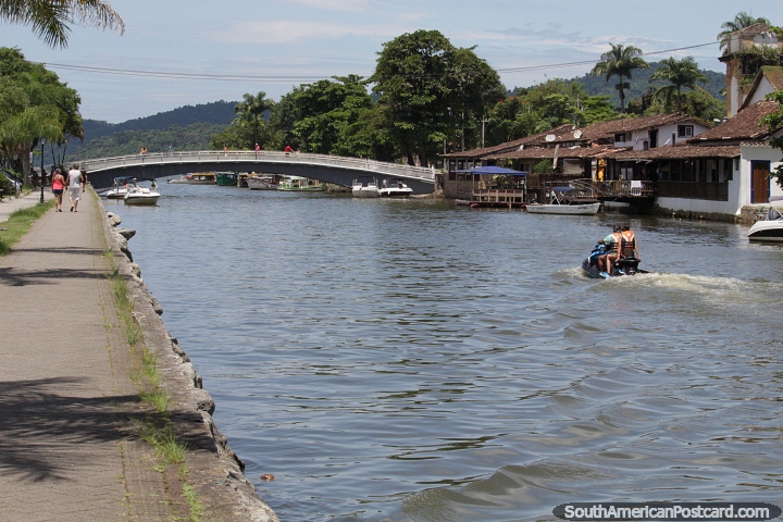 Jet ski cruises along the river towards a bridge in Paraty. (720x480px). Brazil, South America.