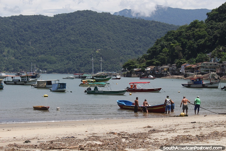 Local fishermen put a boat into the water at the beach in Mangaratiba. (720x480px). Brazil, South America.