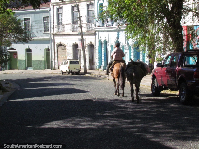 Man trots by on a horse with a donkey on a steep street in Valparaiso. (640x480px). Chile, South America.