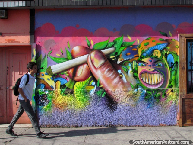 Strange and crazy wall mural in Arica, boy walks past. (640x480px). Chile, South America.