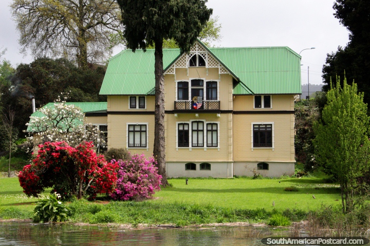 German wooden house beside the river in Valdivia, seen on the City Tour by boat, colorful trees. (720x480px). Chile, South America.