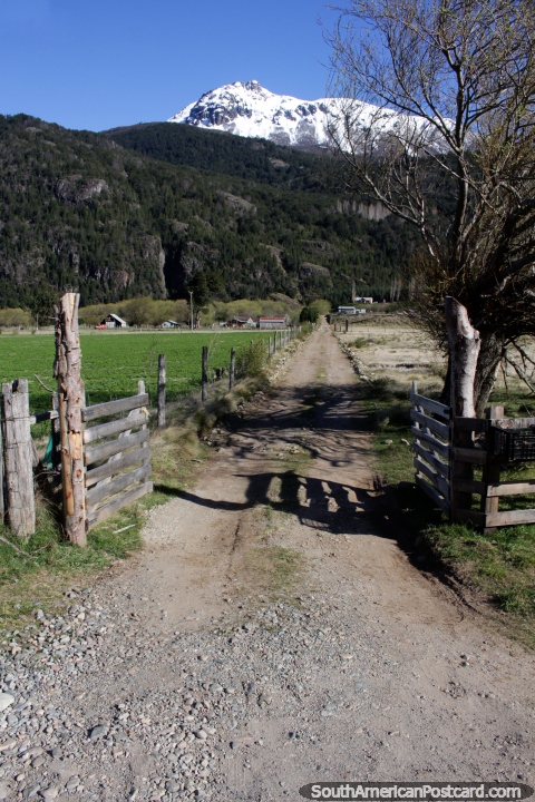 Largo camino de grava hasta una comunidad de casas debajo de las montañas alrededor de Futaleufú. (480x720px). Chile, Sudamerica.