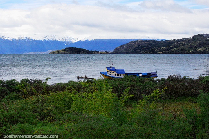 Barco de madeira junto das águas de Lago Carrera Geral, montanhas cobertas de neve atrás, Porto Rio Tranquilo. (720x480px). Chile, América do Sul.