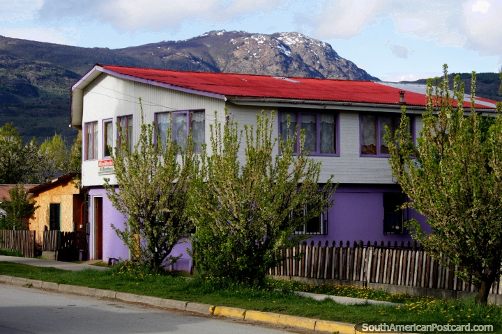 Mini-mercado abajo y una casa en la parte superior, techo rojo, montañas detrás, Cochrane. (720x480px). Chile, Sudamerica.