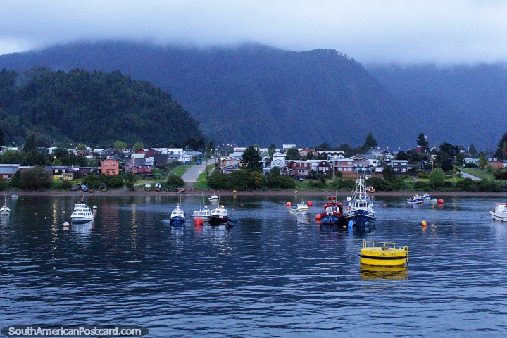 Puerto Cisnes, boats moored in the bay, houses in front of the hills, journey by ferry. (720x480px). Chile, South America.