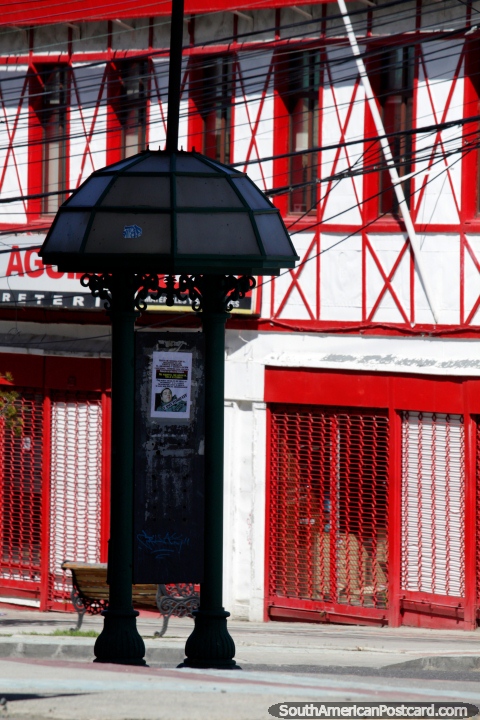 Fachada roja y blanca brillante y una cabina telefónica abovedada en Punta Arenas. (480x720px). Chile, Sudamerica.