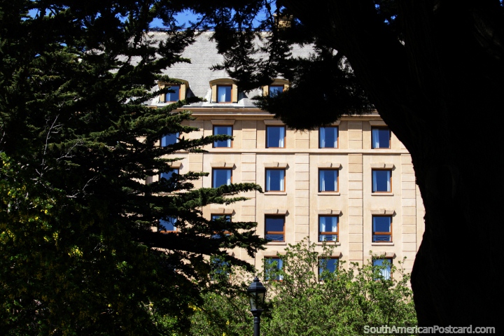 Modern building with many windows, view through the trees in Punta Arenas. (720x480px). Chile, South America.