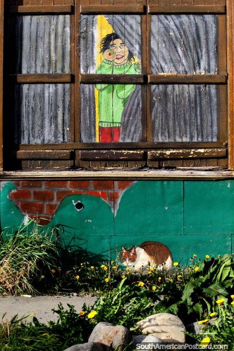 El hombre mira por la ventana, un gato afuera, el arte callejero en Punta Arenas. (480x720px). Chile, Sudamerica.