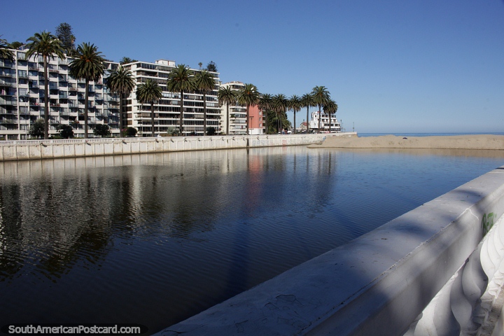 The estuary meets the beach in Vina del Mar, with palm trees and building beside. (720x480px). Chile, South America.