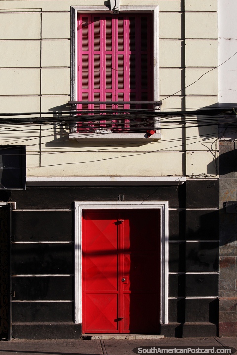 Contraventanas rosas sobre una puerta roja en la fachada de un edificio en Bellavista en Santiago. (480x720px). Chile, Sudamerica.