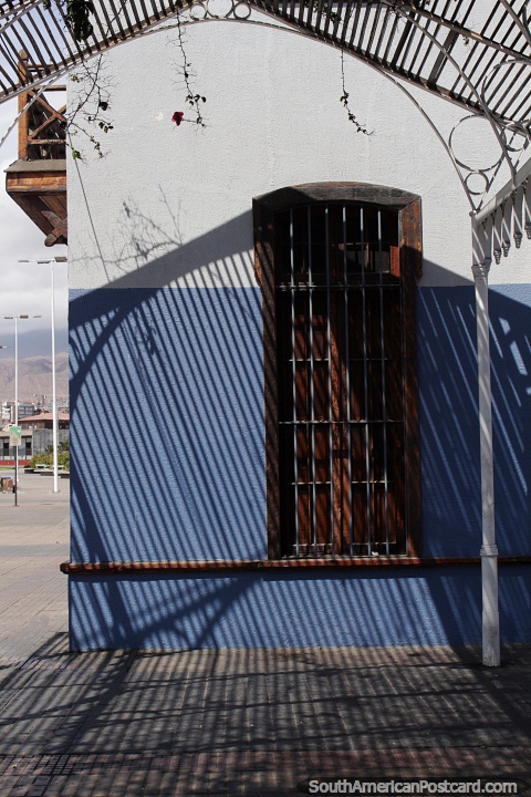 Shadows and light on a building side with wooden window shutters in Antofagasta. (480x720px). Chile, South America.