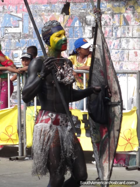 Guerrero con lanza y escudo y pintura de la cara amarilla, verde y roja en Carnaval Barranquilla. (480x640px). Colombia, Sudamerica.