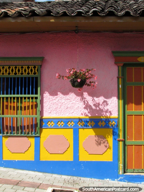 A casa rosa fica em frente em na luz solar, telhado coberto com telhas bonito, uma bela fachada em Guatape. (480x640px). Colômbia, América do Sul.