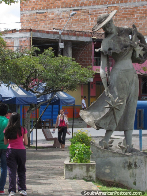 La alta estatua de la mujer mira abajo sobre mujeres más cortas que andan a lo largo de Malecon en Guatape. (480x640px). Colombia, Sudamerica.