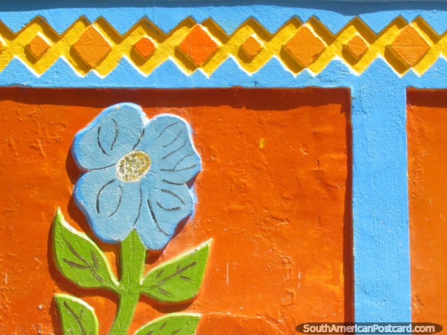 Flor azul, pano para saia de folhas verde e parede cor-de-laranja em Guatape. (640x480px). Colmbia, Amrica do Sul.