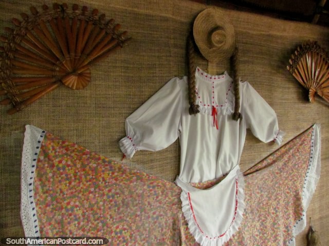 Traditional clothes and hand-held fans hang on the wall at a restaurant in Armenia. (640x480px). Colombia, South America.
