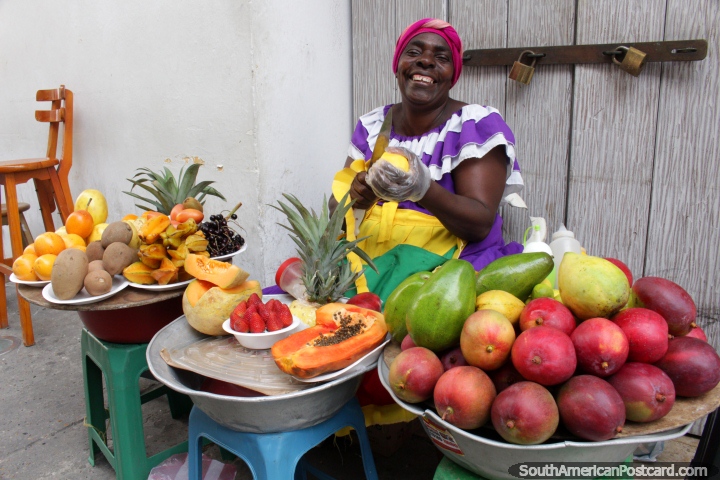 The beautiful smiling fruit lady of Cartagena prepares fruit for sale on the street. (720x480px). Colombia, South America.