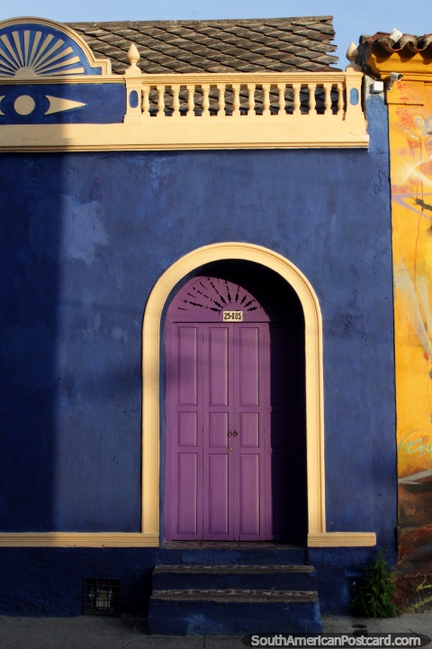 Fachada azul con una puerta púrpura arqueada, pequeña y bonita casa en Cartagena. (480x720px). Colombia, Sudamerica.