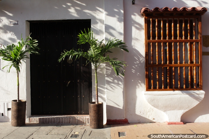 Frente de la casa con un par de plantas y rejas de madera en las ventanas, de Cartagena. (720x480px). Colombia, Sudamerica.