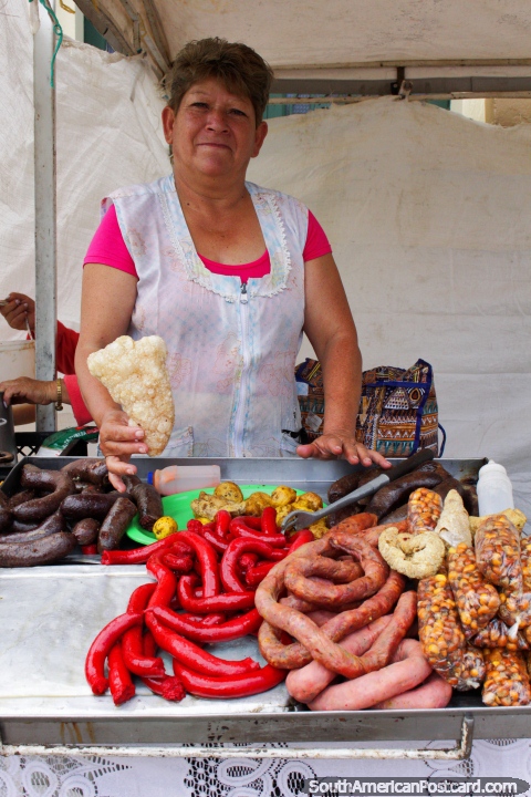 La mujer muestra su gama de salchichas de carne y crujiente de cerdo para desayunar en Tunja. (480x720px). Colombia, Sudamerica.
