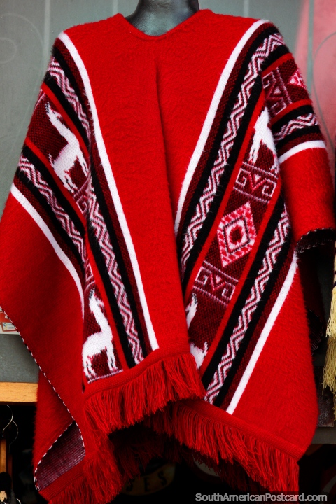 Traditional red shawl with white llamas, worn by men, for sale in Tunja. (480x720px). Colombia, South America.
