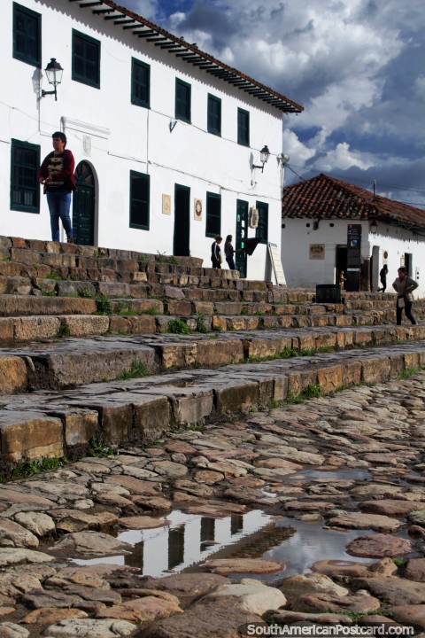 Reflexão de um edifïcio branco nas pedras arredondadas de prefeito de Praça pública em Villa de Leyva. (480x720px). Colômbia, América do Sul.