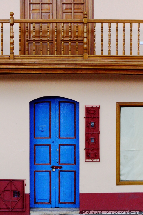 Colorful blue door and natural wooden balcony and door above in Zipaquira. (480x720px). Colombia, South America.