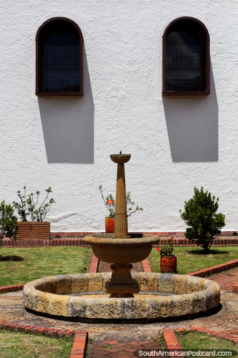 A fonte de pedra e os jardins na igreja fundam em Guatavita. (480x720px). Colômbia, América do Sul.