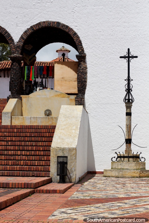 Torre distante a través de un arco, una cruz de acero y escaleras de ladrillo rojo en Guatavita. (480x720px). Colombia, Sudamerica.