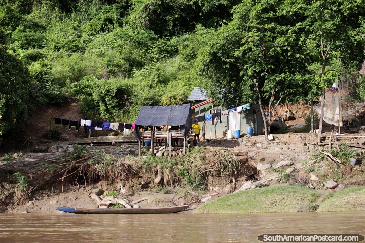 Riverside house and front yard with wooden canoe and clothes drying, Magdalena River, Girardot. (720x480px). Colombia, South America.