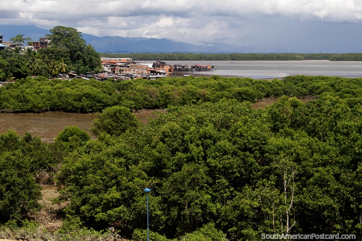The green coastline in Buenaventura with wooden seaside shacks on stilts in the distance. (720x480px). Colombia, South America.