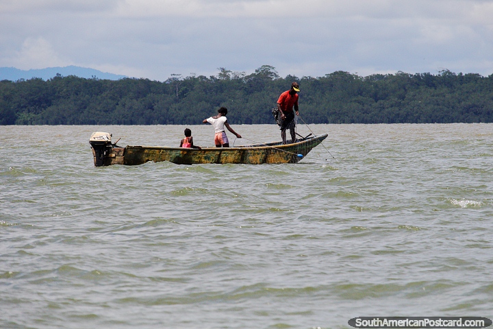 El hombre y las hijas tiran de una red de pesca desde su pequeña embarcación frente a la costa de Buenaventura. (720x480px). Colombia, Sudamerica.