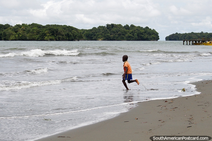 O rapaz local da praia de Juanchaco corre em direção ao mar, Costa do Pacïfico ao norte de Buenaventura. (720x480px). Colômbia, América do Sul.