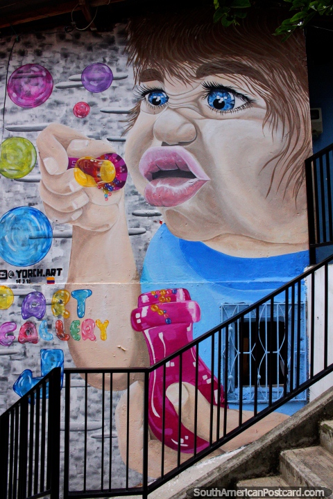 Child blows colored bubbles, art in the streets of Comuna 13 in Medellin. (480x720px). Colombia, South America.