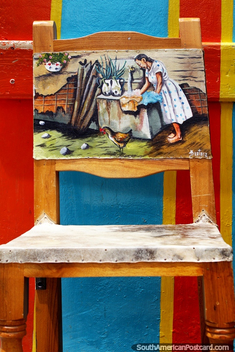 Pintura de una dama lavando ropa en el respaldo de un asiento en Jardin, arte cultural. (480x720px). Colombia, Sudamerica.