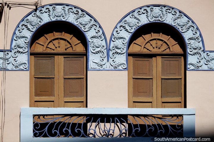 Arcos decorados en azul sobre un par de puertas de madera marrón y un balcón, arquitectura en Pereira. (720x480px). Colombia, Sudamerica.