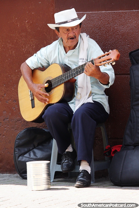 Homem toca violão e canta na rua em Pereira, roupa elegante. (480x720px). Colômbia, América do Sul.