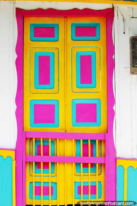 Bright door in pink, yellow and teal in the colorful streets of Salento. (480x720px). Colombia, South America.