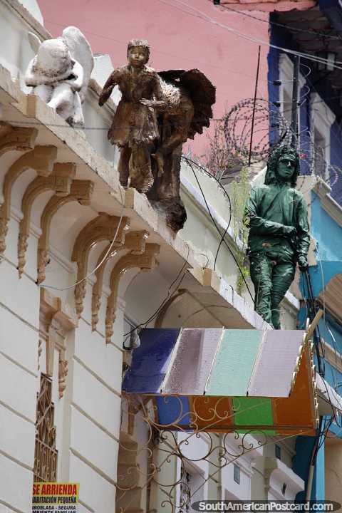 2 figuras estão nos telhados acima da rua em La Candelaria, em Bogotá, observe de perto, há uma terceira. (480x720px). Colômbia, América do Sul.