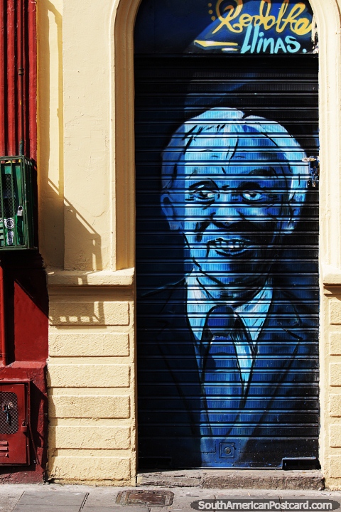 Homem azul de terno pintado na porta de enrolar de uma loja em Bogotá. (480x720px). Colômbia, América do Sul.