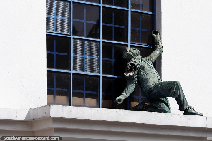 Is he trying to escape? Bronze figure on a ledge beside windows, art in Bogota. (720x480px). Colombia, South America.